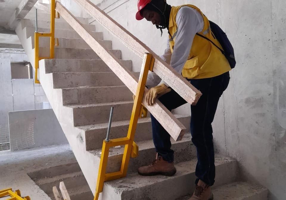 Operario instalando guardacuerpo amarillo en escalera